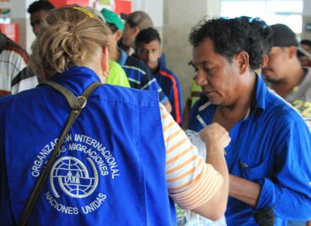 IOM official provides support to migrants lining up for supplies
