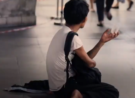 Persona adulta sentada en una calle solicitando dinero